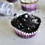 A cupcake in a purple wrapper and topped with a delicious homemade black frosting