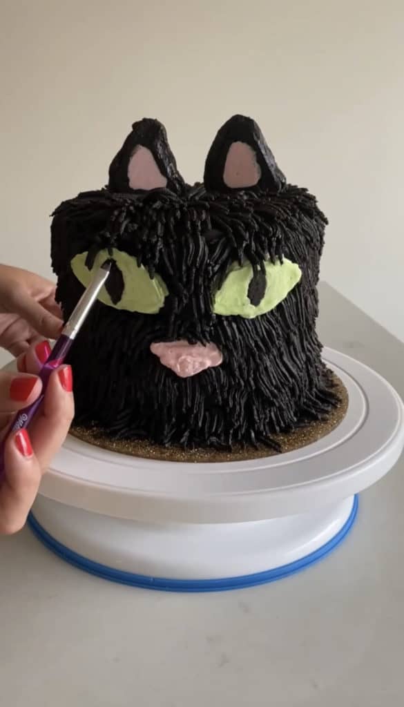 finishing touches with food gel and paintbrush for black cat cake design