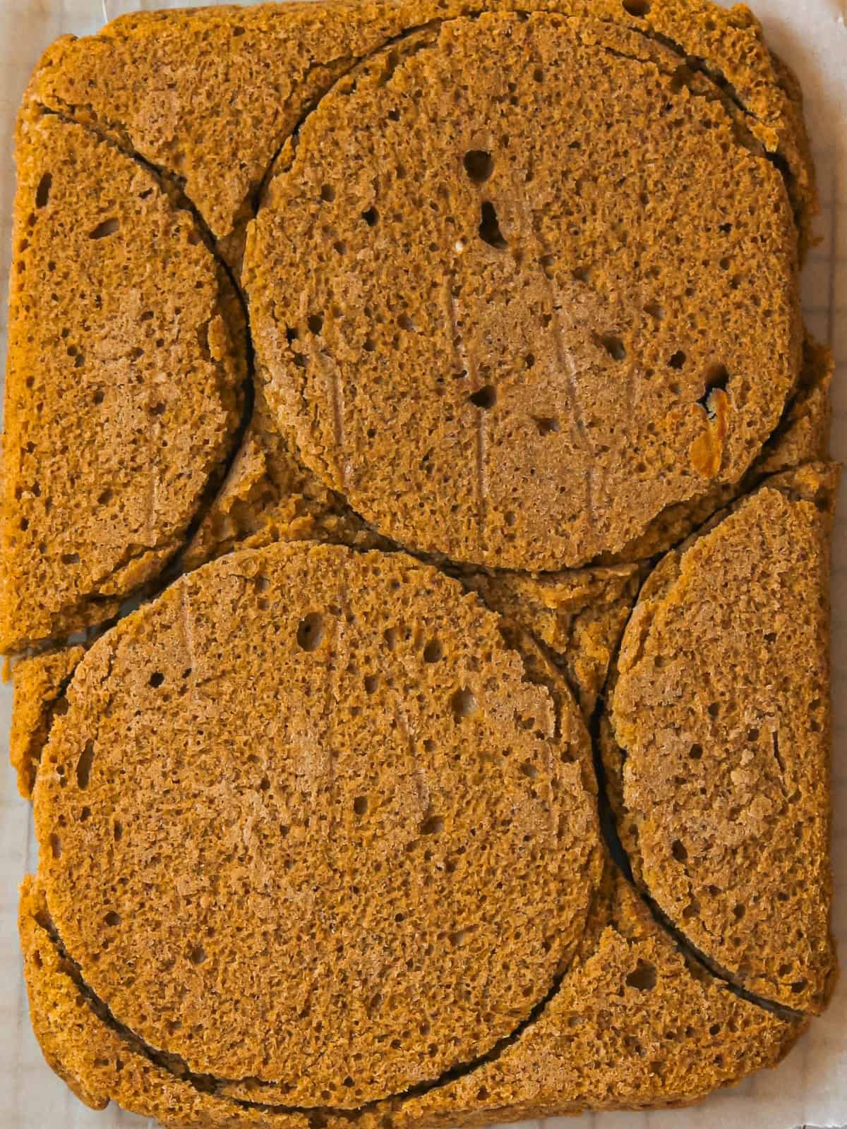 Overhead image of baked pumpkin chai cake, with the circles of the cake all cut and ready to be stacked.