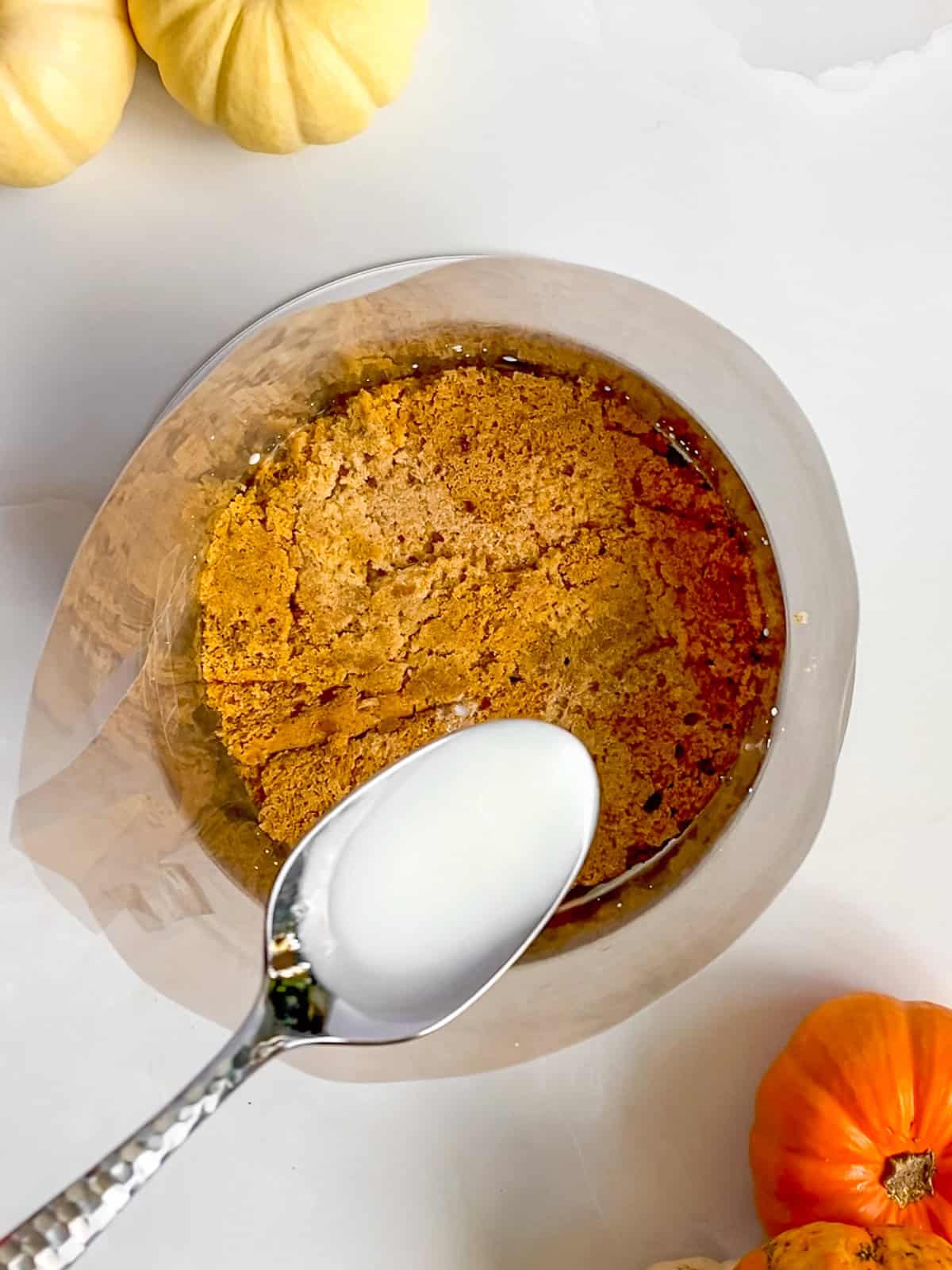 Spooning the milk soak over the bottom layer of pumpkin chai cake.