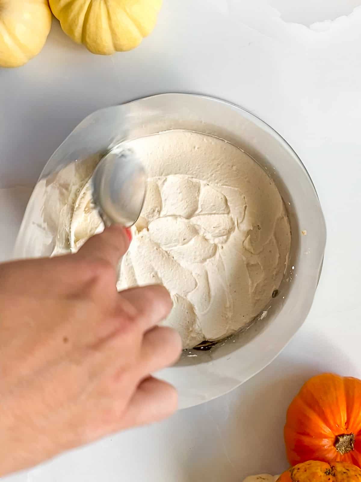 Spreading mascarpone frosting evenly across the pumpkin chai cake layer.