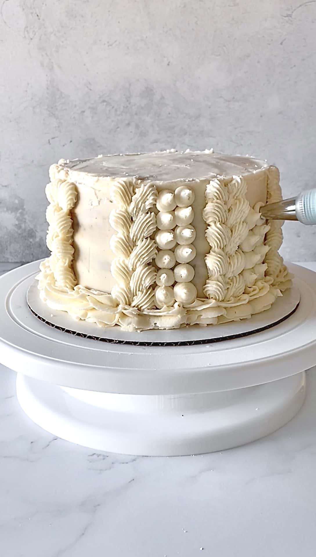 piping dots on sides of textured buttercream cake