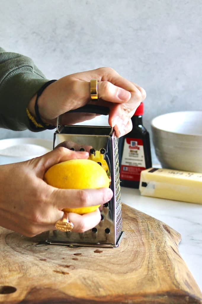 Zesting lemon on a grater for mini lemon Bundt cakes