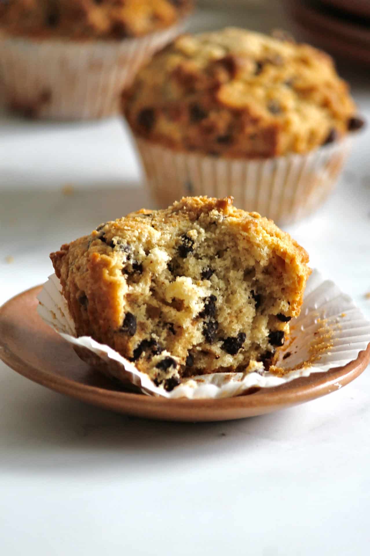 Bakery style chocolate chip muffins with a bite missing from one