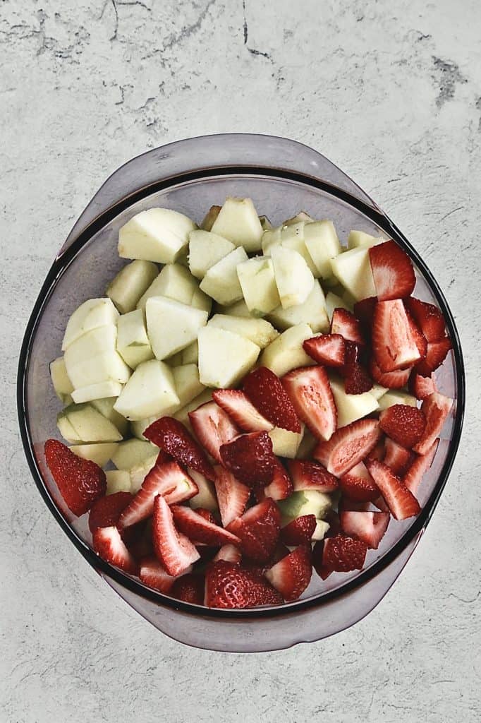 chopped apples and strawberries in a bowl for the fruit crumble