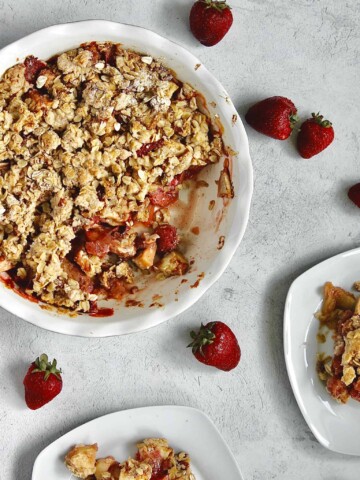 image of baked strawberry apple crumble alongside two small plates of individual servings