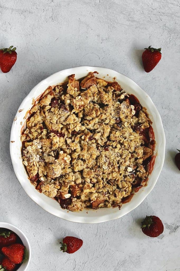 baked fruit crisp with strawberries around the dish