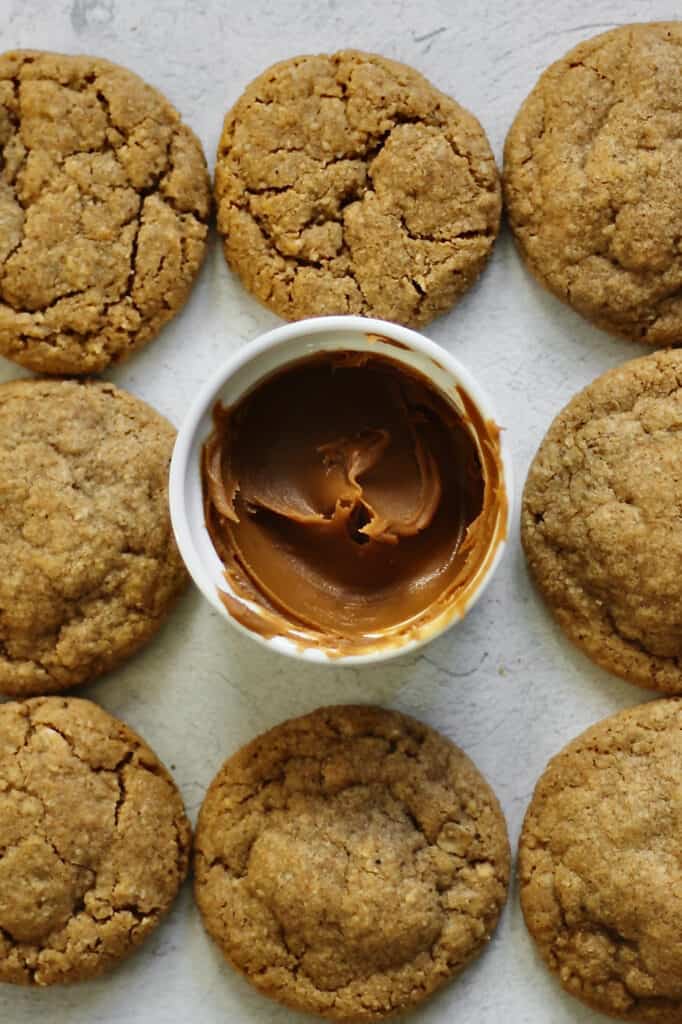 baked cookies on a tray with Biscoff spread in the middle of it in a white ramekin