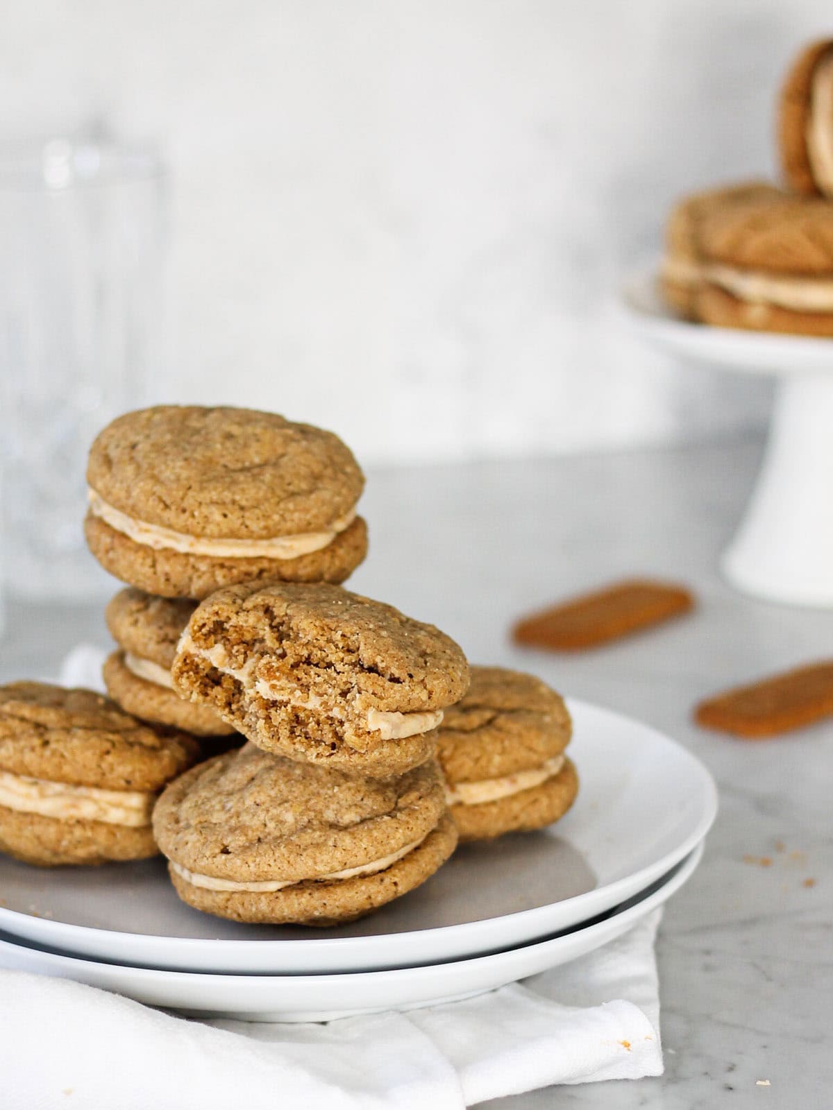 Soft and chewy Biscoff sandwich cookies filled with cookie butter frosting, showing the inside of a bitten cookie.