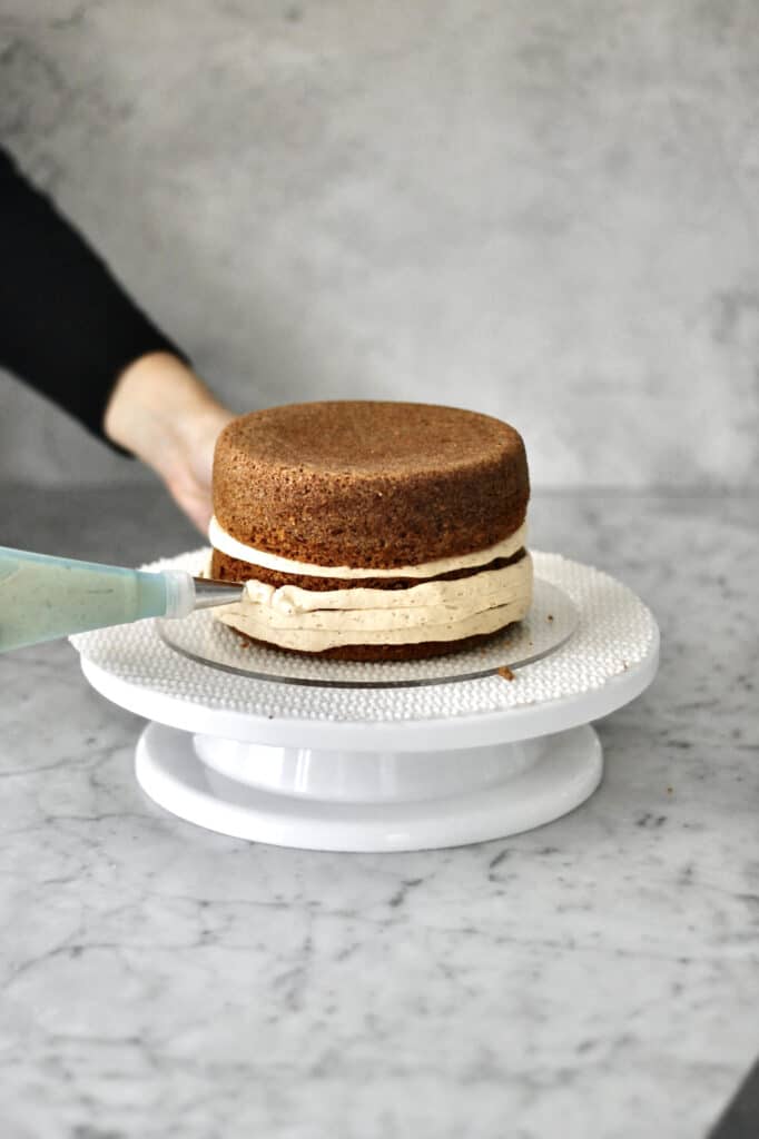 spreading frosting on the outside of both layers of Lotus Biscoff cake