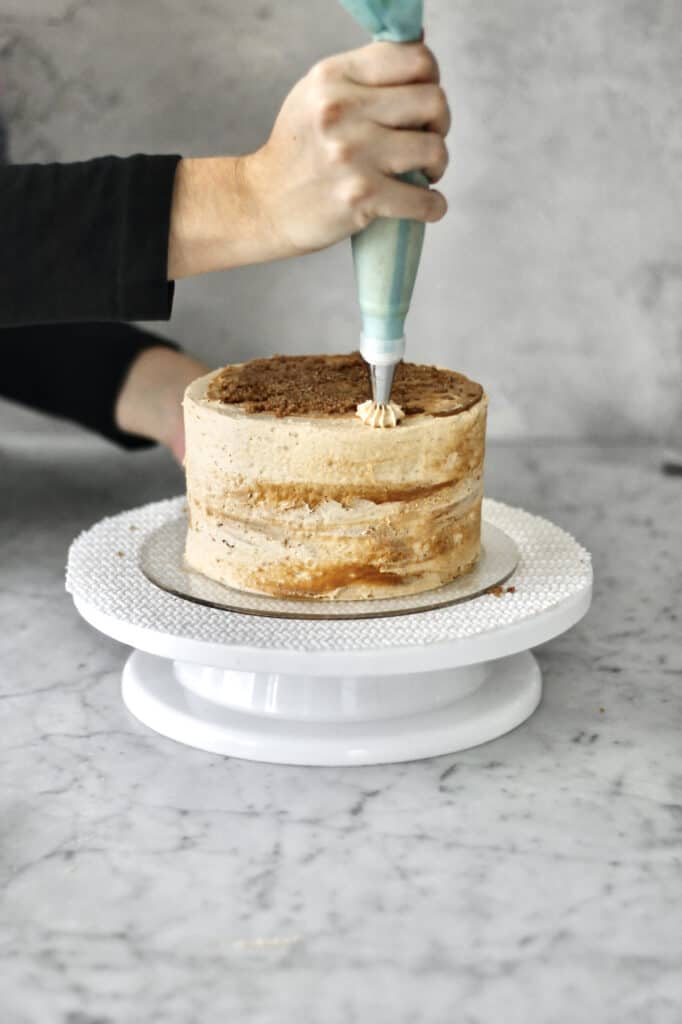 piping design onto top of layered Biscoff cake