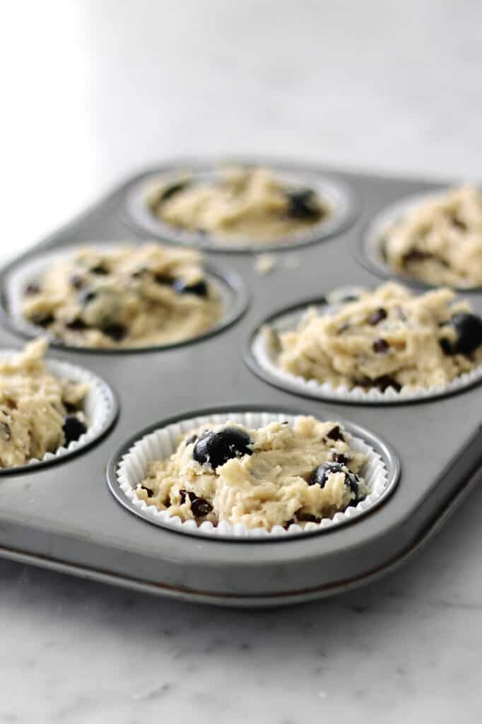 overhead shot of a muffin tin filled with blueberry chocolate chip muffins