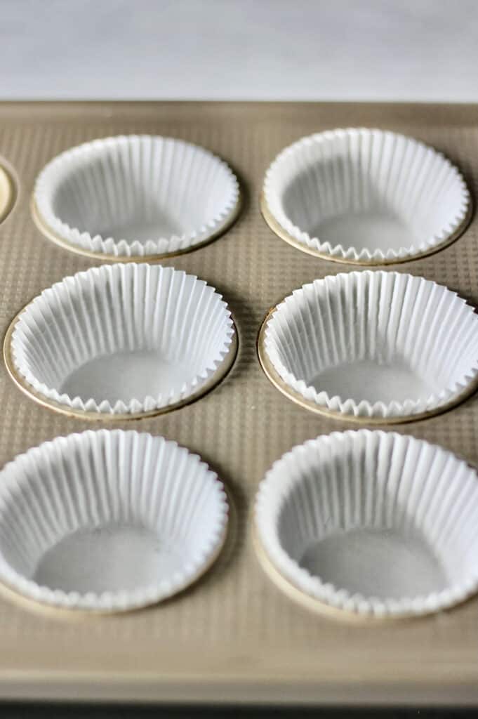 white muffin liners in a gold pan, ready to be filled with cupcake batter
