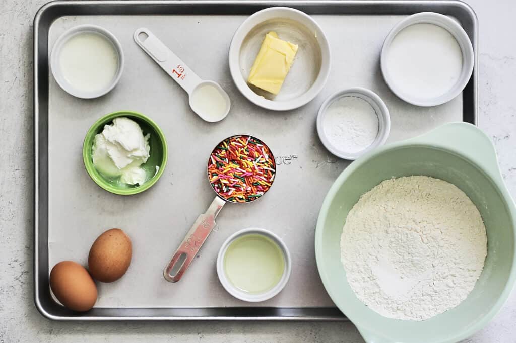overhead shot of ingredients for funfetti muffins on an aluminum baking tray