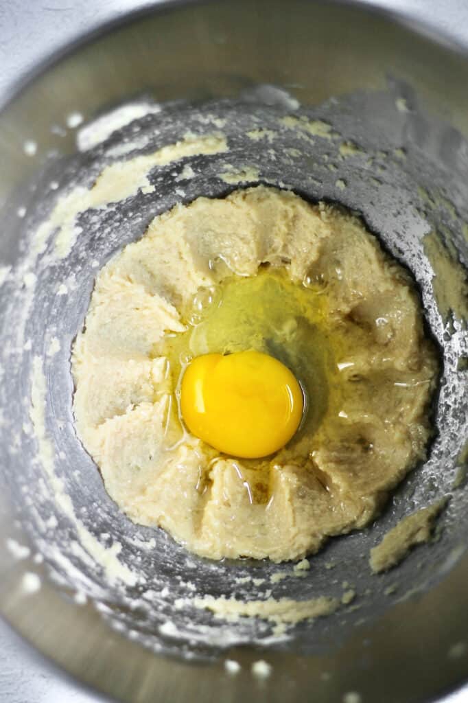 vanilla cupcake batter in progress, with an egg waiting to be mixed into it
