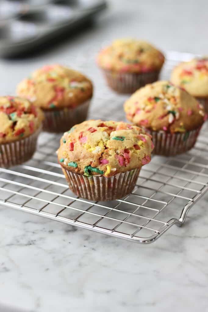 image of sprinkle muffins sitting on a wire rack to cool after exiting the oven