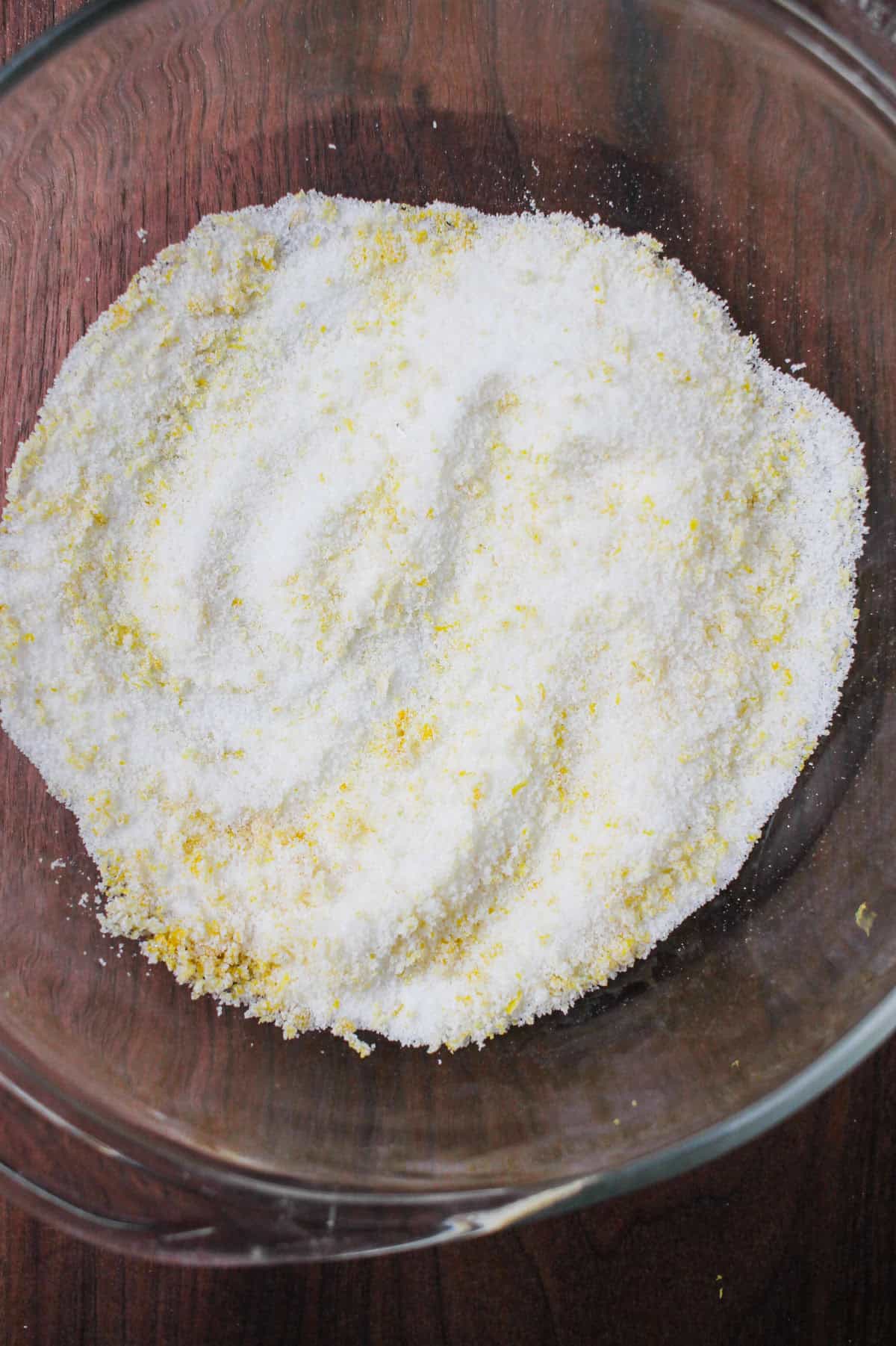 Infused lemon zest in a bowl of sugar.