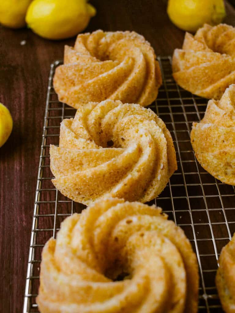Small yellow cakes cooling on a wire rack.
