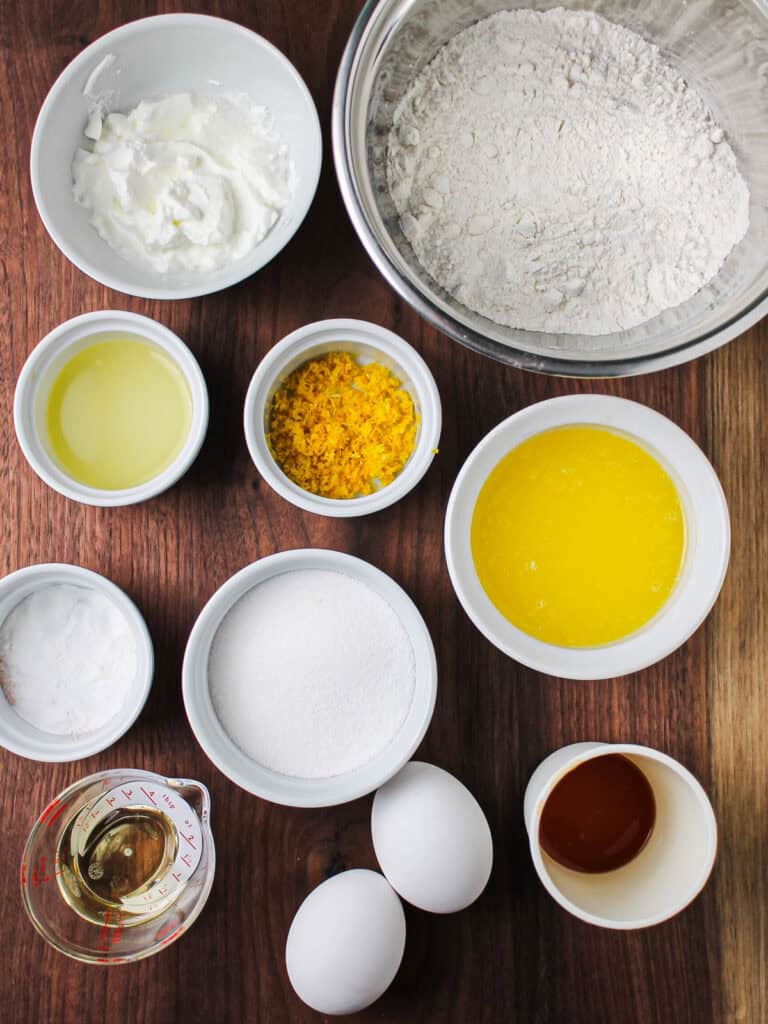 Overhead shot for the ingredients for mini lemon Bundt cakes, sitting against a wooden cutting board.