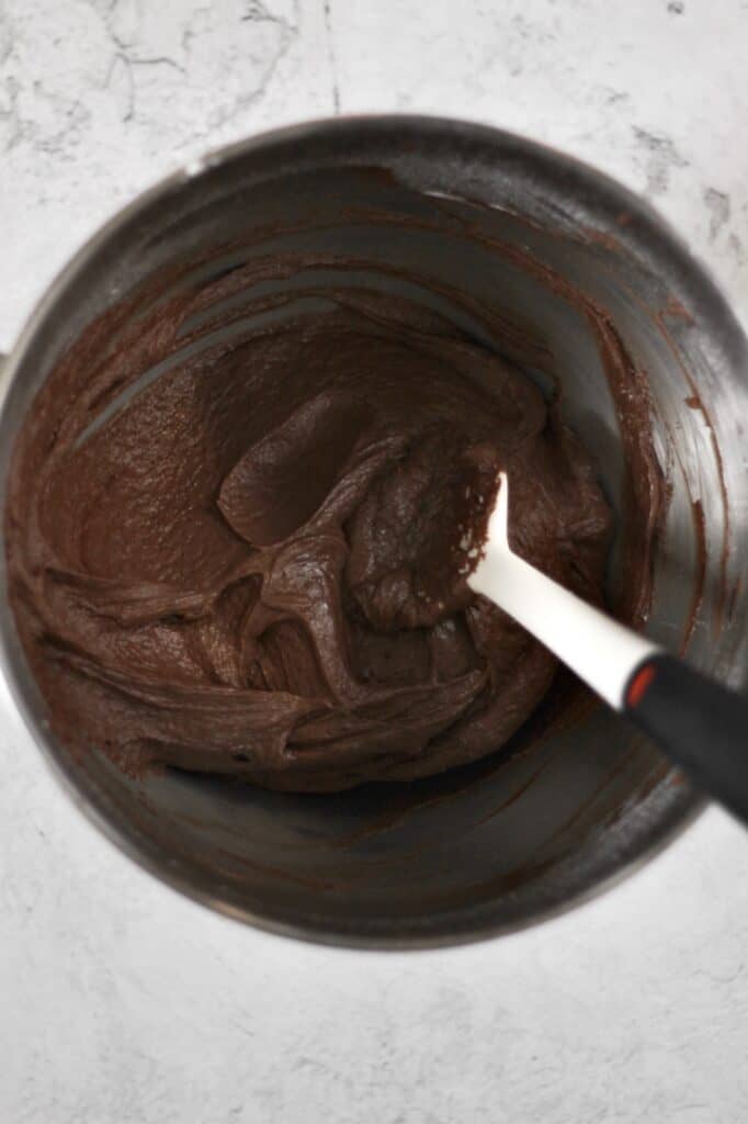 overhead image of chocolate cream cheese frosting ingredients, all combined and smooth in one mixing bowl