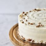 up-close image of the side of my pineapple carrot cake, with crushed pecans on the top and around its base