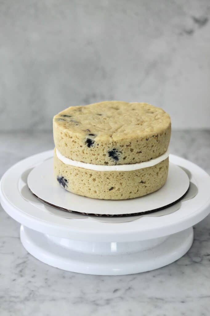 cake turntable with two layers of lemon and blueberry cake on it