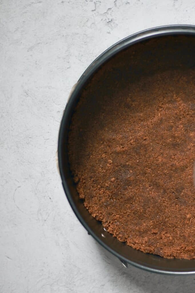overhead image of Biscoff Pie Crust pressed into a 9" springform pan on a grey background