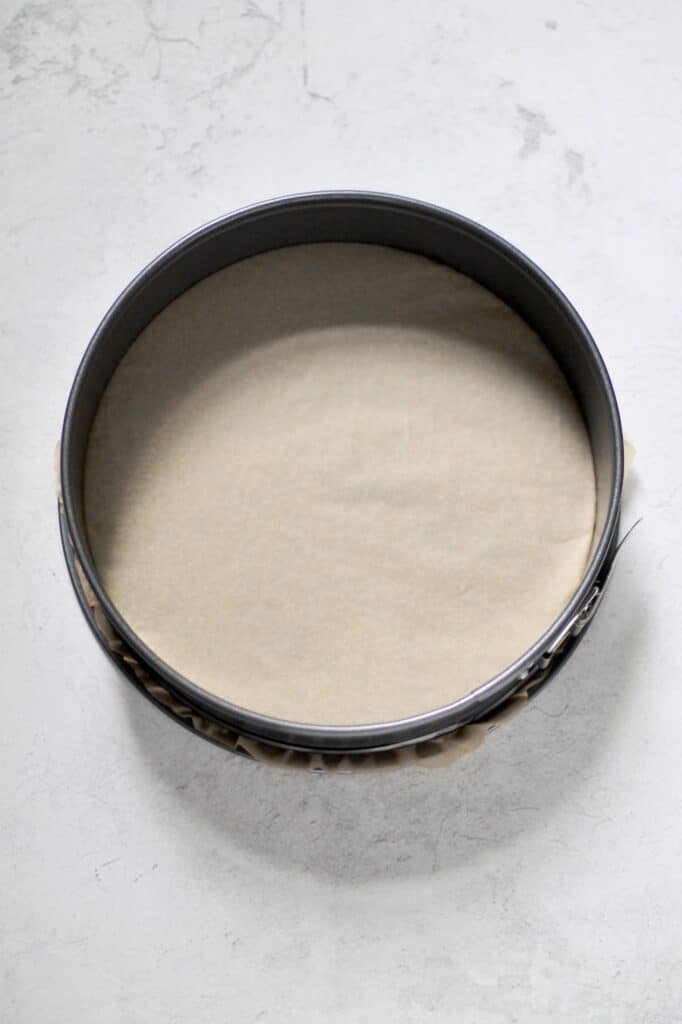 overhead image of a springform pan, lined with parchment paper