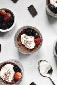 overhead image of chocolate mascarpone mousse in small glasses, topped with whipped cream and berries