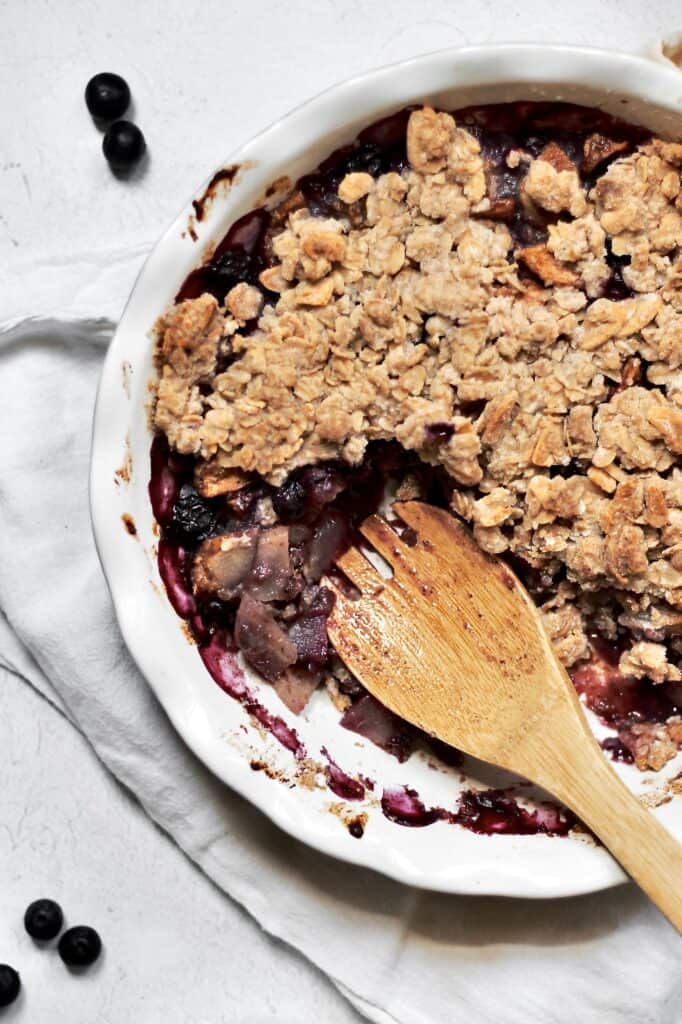 overhead shot of blueberry pear crumble sitting on a white cheesecloth against a grey background