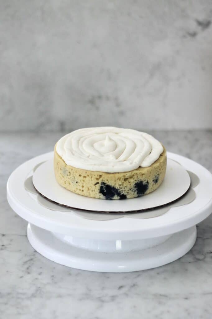 cake turntable with one layer of lemon and blueberry cake on it