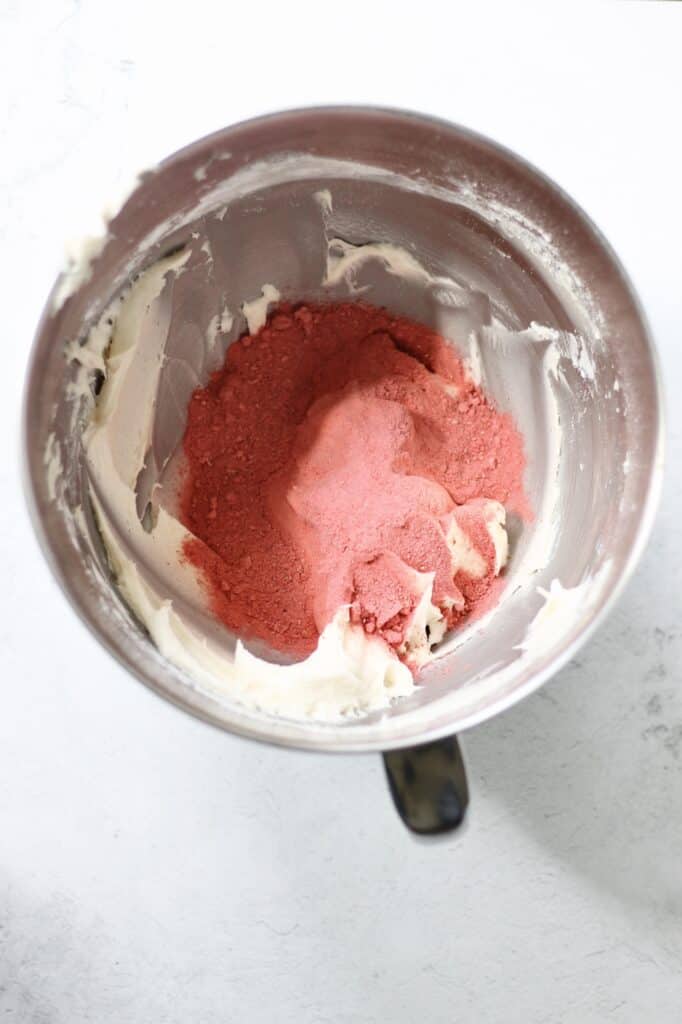 freeze dried strawberry powder in a mixing bowl of cream cheese frosting