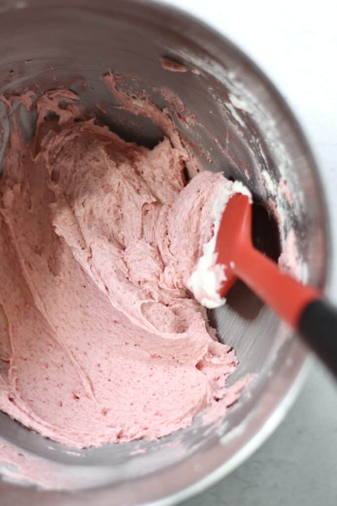 freeze dried strawberry powder combined with cream cheese frosting in a mixing bowl