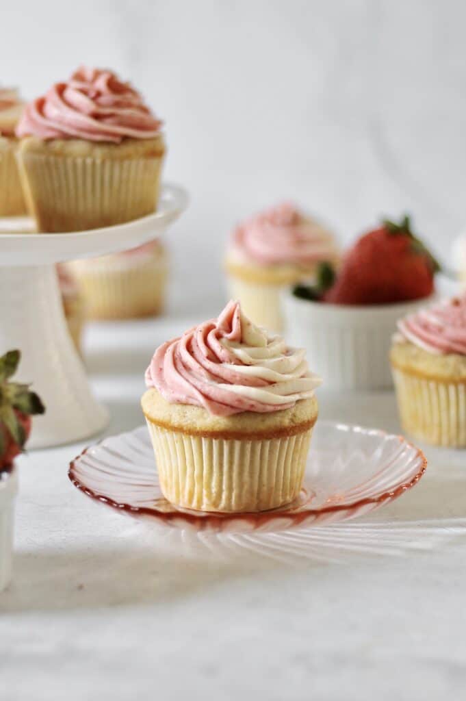 up-close image of a vanilla cupcake decorated with marbled strawberry cream cheese frosting