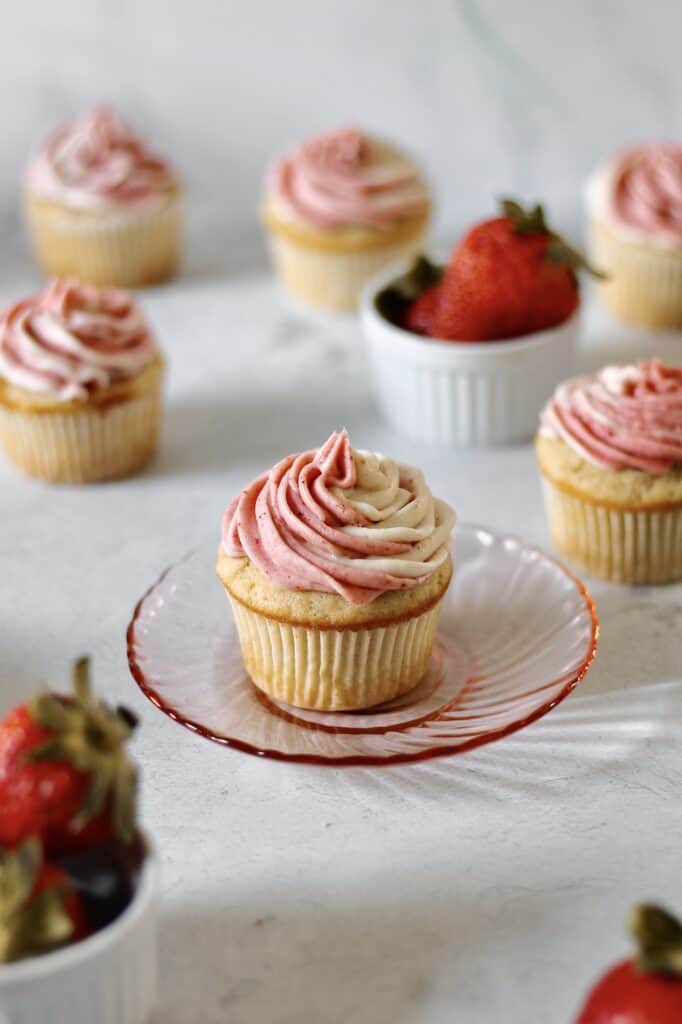 up-close image of strawberry filled cupcake sitting on a small pink plate