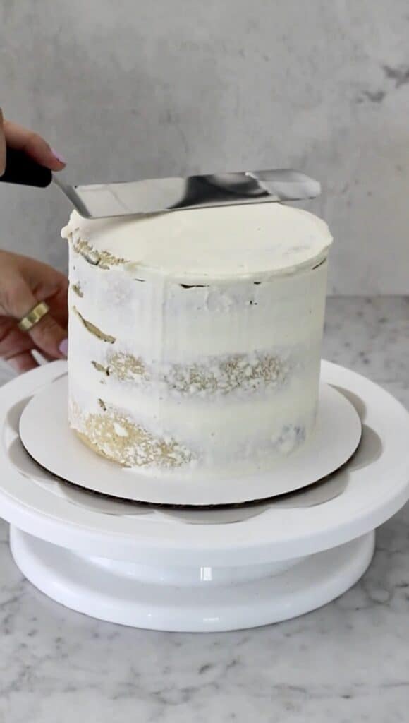 offset spatula smoothing top of white cake