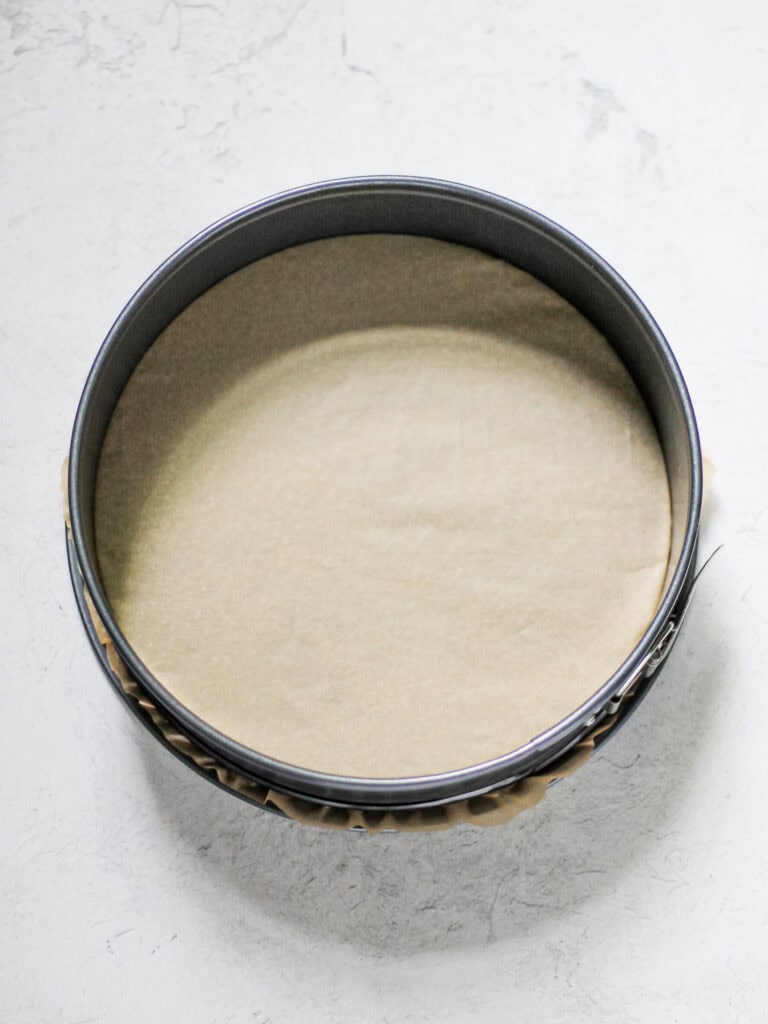 Overhead image of a springform pan, lined with parchment paper.
