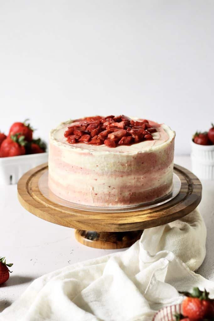 image of pink and white marbled cake, topped with roasted strawberries