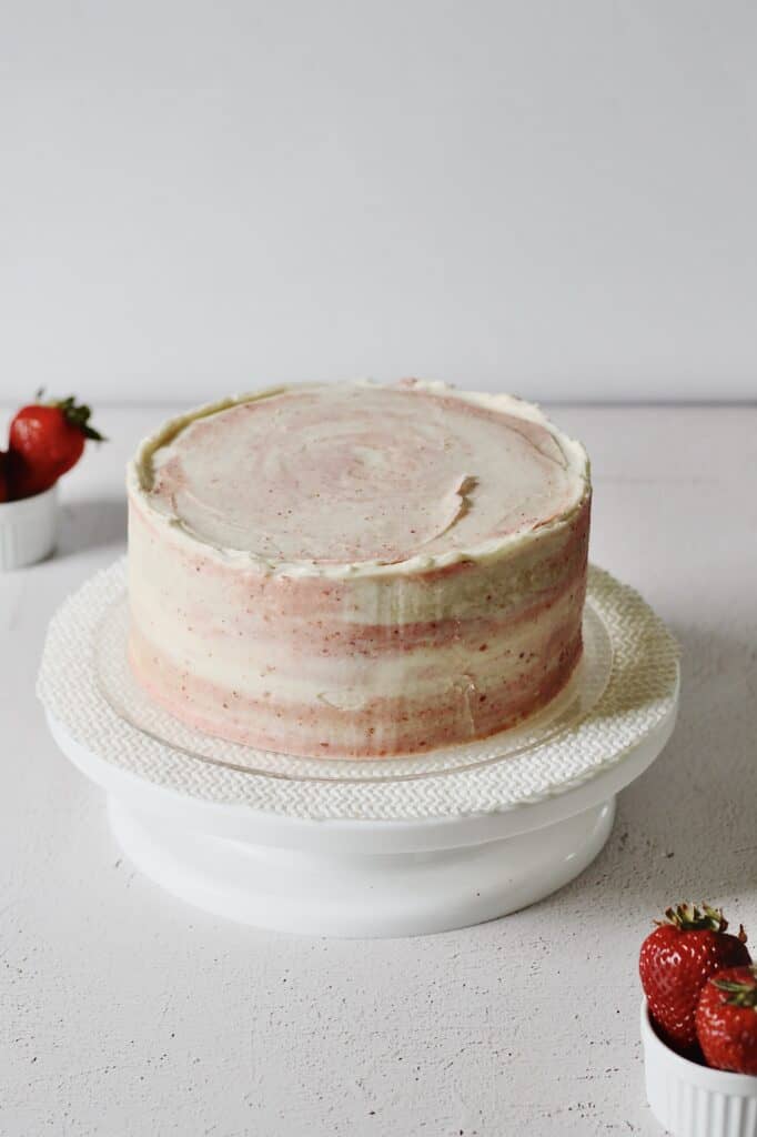 pink and white marbled frosting on vanilla cake with strawberry filling