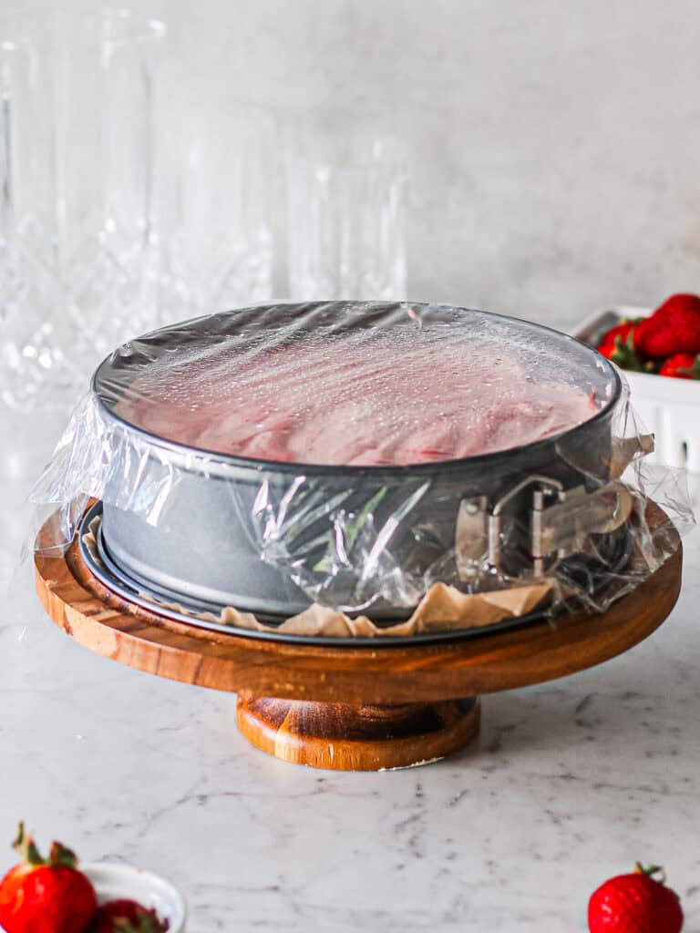Springform pan covered with plastic wrap.