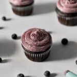 chocolate cupcakes with blueberry cake frosting, surrounded by blueberries