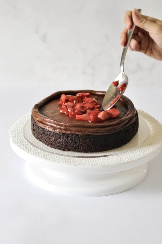 adding strawberry filling to chocolate cake's first layer