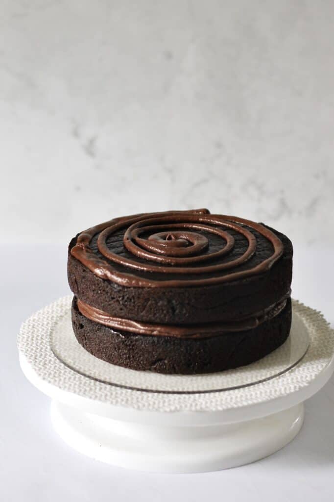 piping ganache onto chocolate layer cake