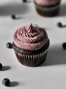 chocolate cupcakes topped with blueberry frosting, surrounded by blueberries