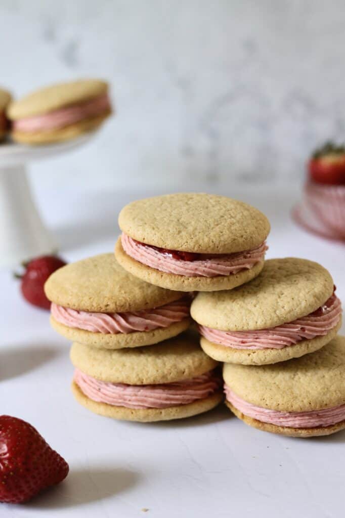 stack of strawberry cookie sandwiches, filled with pink cream cheese frosting