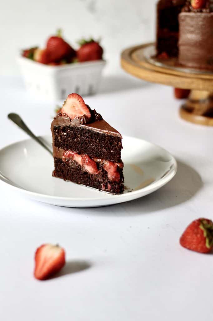 up-close shot of slice of chocolate layer cake with strawberry filling inside it