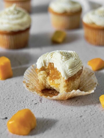 mango cupcake, missing a bite, and showing the filling inside