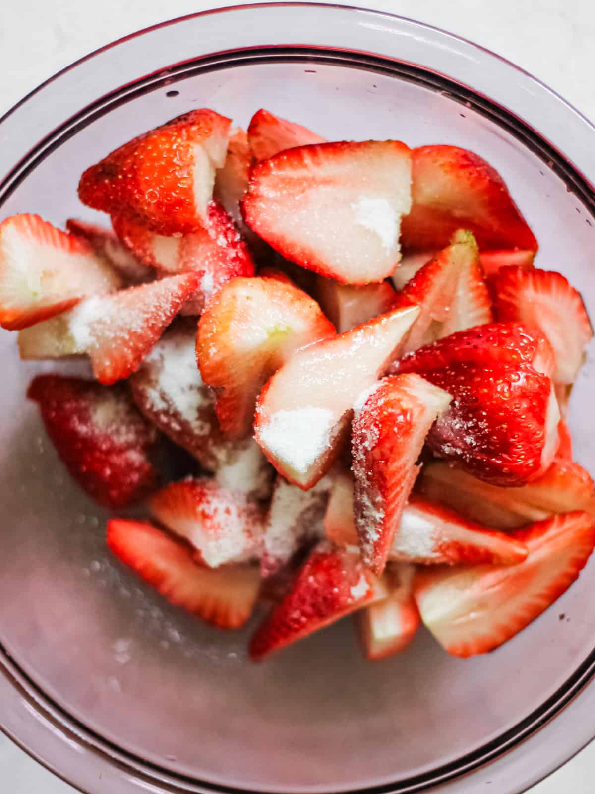 Up-close image of strawberries in bowl with sugar on them.