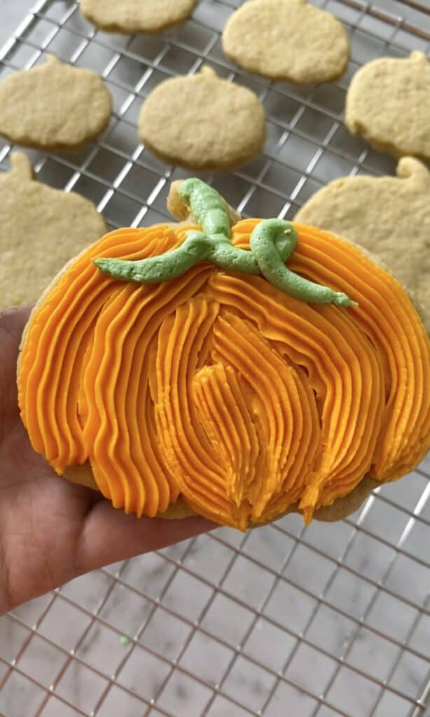 pumpkin sugar cookies, piped with orange frosting and a green vine