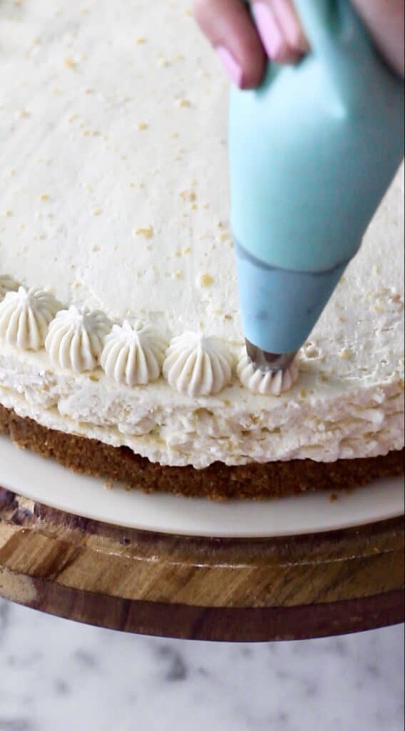 up-close image of action shot, with piping bag adding mango mousse to top of cake